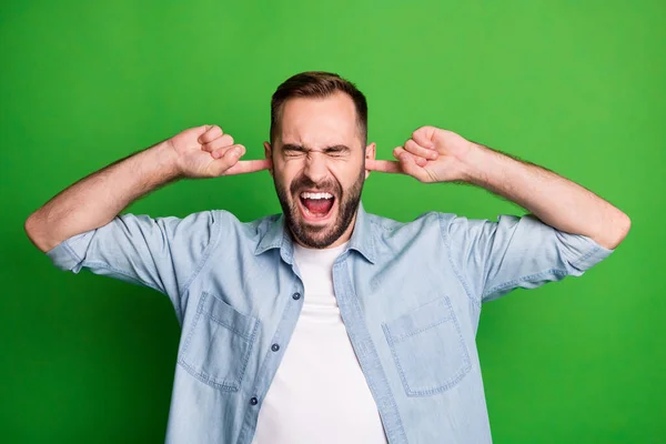 Retrato de hombre triste manos orejas gritar ojos cerrados usar camisa azul aislado en fondo de color verde vibrante — Foto de Stock