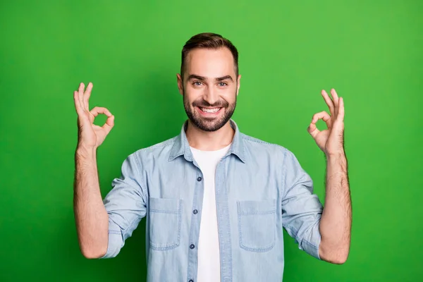 Retrato de hombre divertido optimista usar camisa azul mostrar signos okey aislados sobre fondo de color verde — Foto de Stock