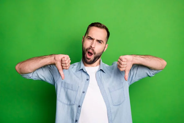 Retrato de hombre triste impresionado usar camisa azul mostrar mala señal boca abierta aislado sobre fondo de color verde — Foto de Stock