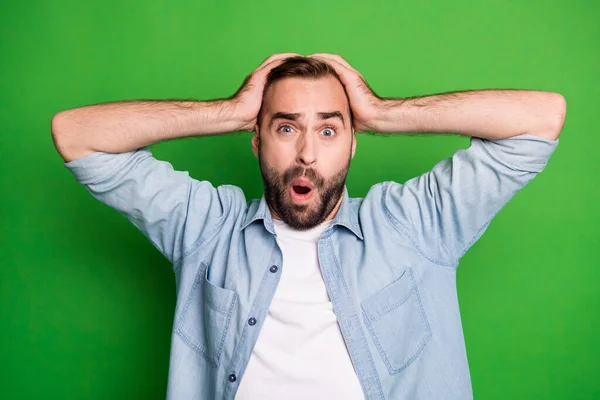 Portret van een onder de indruk trieste man dragen blauw shirt arm hoofd open mond geïsoleerd op groene kleur achtergrond — Stockfoto