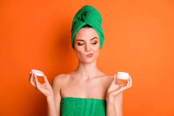 Foto retrato de mulher astúcia segurando em duas mãos olhando para frasco de creme aberto isolado no fundo de cor laranja brilhante — Fotografia de Stock