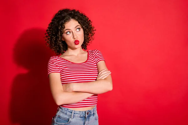 Foto de encantadora dulce mujer joven vestida a rayas brazos cruzados buscando espacios vacíos labios moteados aislados color rojo fondo —  Fotos de Stock