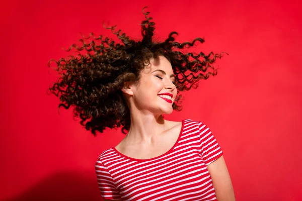 Foto de chica morena rizada positiva sonrisa feliz disfrutar de tratamiento de pelo de salón aislado sobre fondo de color rojo — Foto de Stock