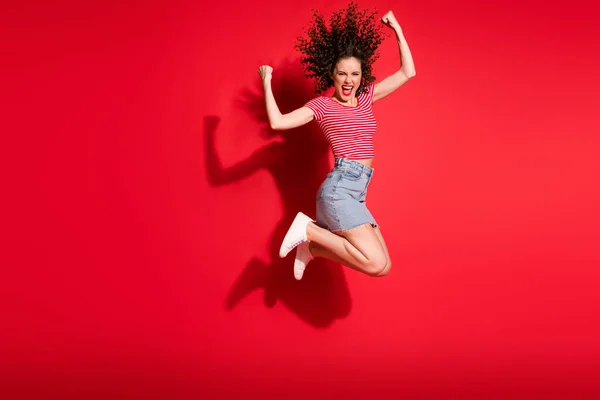 Mutlu gülüşün tam vücut fotoğrafı genç kız zıpla zaferi kutla yumrukları kazan elleri kırmızı arkaplanda izole edilmiş — Stok fotoğraf