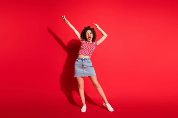 Фотографія повного тіла молодої дівчини з позитивною посмішкою отримуйте задоволення від танцювальних рук вгору X-mas ізольовано на фоні червоного кольору — стокове фото