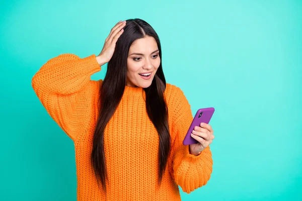 Foto von erstaunt Mädchen halten Handy-Look Bildschirm offenen Mund tragen orangefarbenen Pullover isoliert Krickente Farbe Hintergrund — Stockfoto