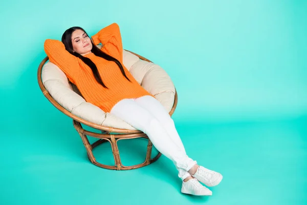 Foto de la joven inspirada poner la silla manos detrás de la cabeza desgaste jersey naranja aislado color verde azulado fondo —  Fotos de Stock