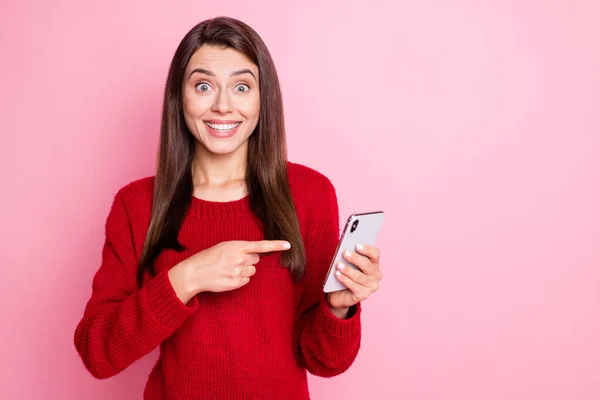 Foto de menina bonito indicar dispositivo dedo segurar smartphone desgaste pulôver vermelho isolado cor-de-rosa fundo — Fotografia de Stock