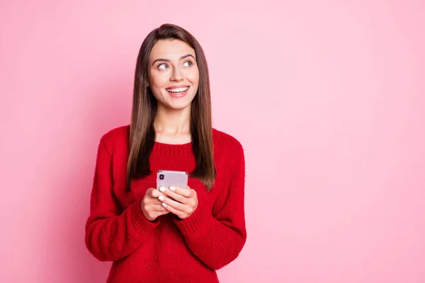 Foto di affascinante ragazza tenere telefono cercare spazio vuoto indossare maglione rosso isolato colore rosa sfondo — Foto Stock