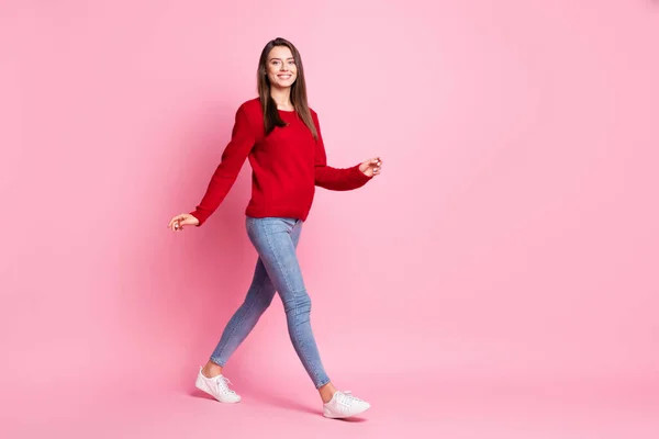 Фотографія профілю милої молодої леді, яка збирається дивитися камеру, носить червоний светр джинси кросівки ізольовані рожевий колір фону — стокове фото
