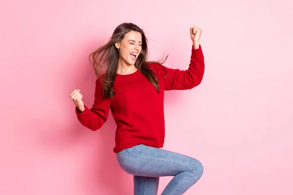 Foto di bella ragazza occhi chiusi bocca aperta alzare le braccia ginocchio usura rosso maglione jeans denim isolato colore rosa sfondo — Foto Stock