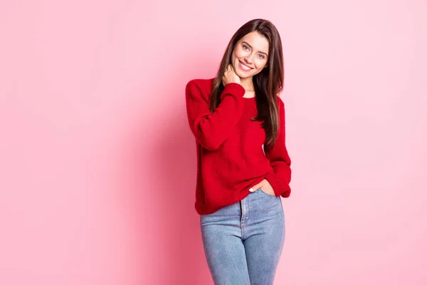 Фотографія молодої милої леді руки шиї кишені білого кольору, що посміхається, виглядає як камера, одягнена в червоний светр джинси ізольовані рожевий колір фону — стокове фото