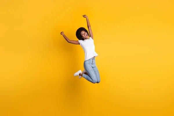 Full längd kroppsstorlek foto av roliga vackra kvinnliga millennial med svart hud hoppa högt hålla händerna över huvudet isolerad på ljusa gula färg bakgrund — Stockfoto