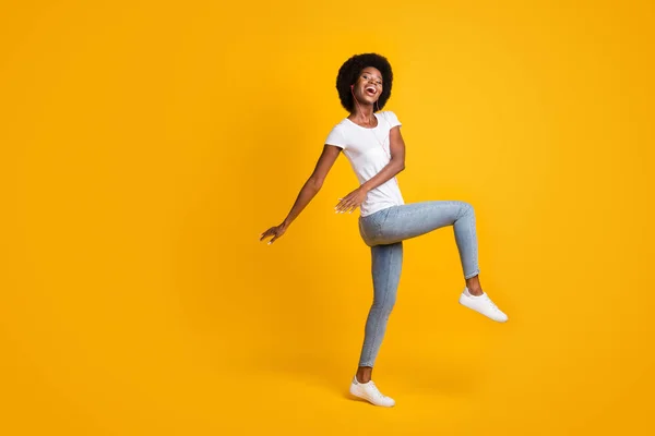 Teljes hossz testméret fotó pozitív fiatal nő fekete bőr hallgat dal tánc narancs fülhallgató elszigetelt élénk sárga színű háttér üres hely — Stock Fotó