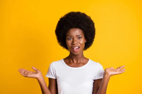 Foto porträtt av okunnig afrikansk amerikansk kvinna undrar hålla händerna åt sidan med öppen mun bär vit t-shirt isolerad på ljusa gula färgade bakgrund — Stockfoto