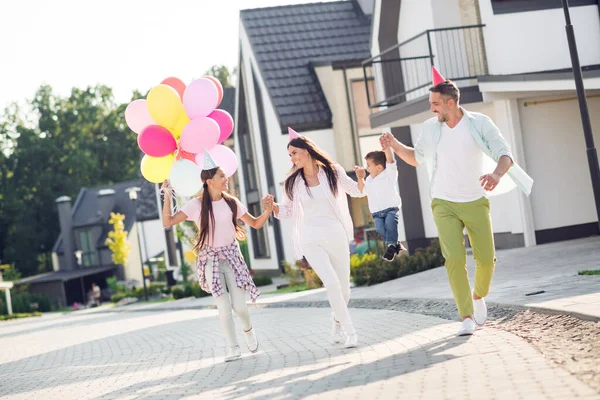 Foto de cuerpo completo de la familia mamá papi niños ir caminar correr sonrisa feliz disfrutar de la celebración usar sombrero fiesta vacaciones globos de aire infancia — Foto de Stock