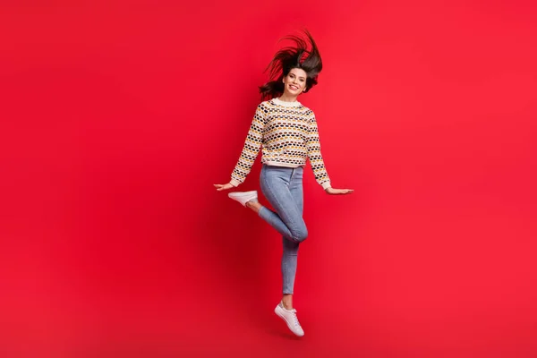 Longitud completa tamaño del cuerpo foto de niña descuidada infantil saltando con el pelo que sopla sonriendo aislado color rojo brillante fondo — Foto de Stock