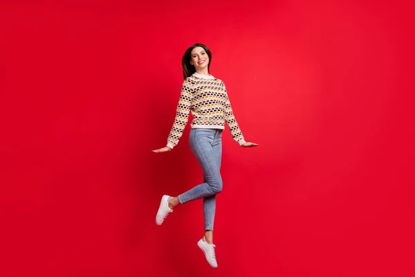 Comprimento total do corpo tamanho foto de menina bonita agradável pulando vestindo roupas elegantes jeans camisola isolado vívido cor vermelha fundo — Fotografia de Stock