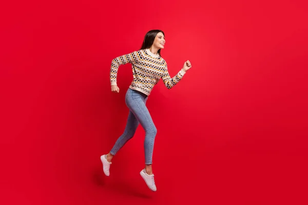 Фотографія повного розміру тіла дівчини в светрі, що швидко стрибає на продаж, посміхаючись ізольований яскраво-червоний кольоровий фон — стокове фото