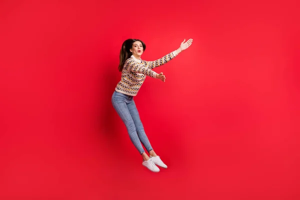 Longitud completa tamaño del cuerpo foto de la chica feliz en suéter saltando soplando viento ciclón aislado vívido color rojo fondo —  Fotos de Stock