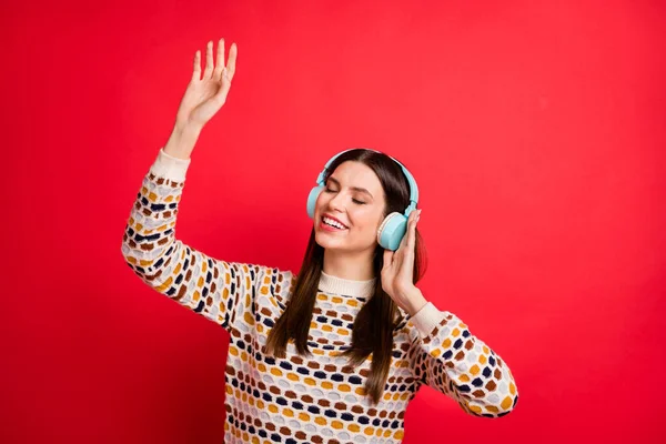 Foto portrét mladé dívky snivé těší hudbu v bezdrátových sluchátek s úsměvem izolované zářivé červené barvy pozadí — Stock fotografie