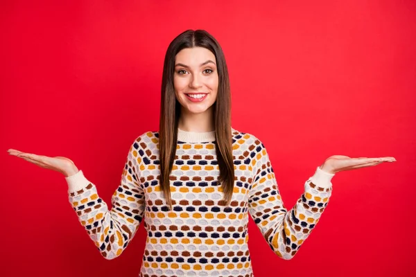 Portrait de fille agréable optimiste tenir l'espace vide porter pull coloré isolé sur fond de couleur rouge — Photo