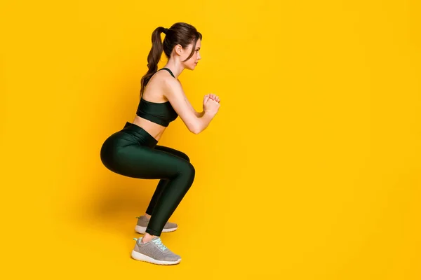 Full body profiel zijkant foto van sportief meisje doen squats sit-ups dragen bijgesneden top slipje geïsoleerd op heldere kleur achtergrond — Stockfoto