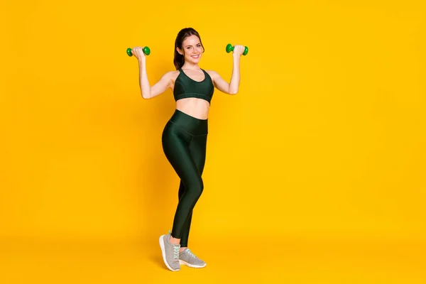 Volledige lichaamsomvang uitzicht van aantrekkelijke vrolijke inhoud meisje tillen halters activiteit geïsoleerd over helder gele kleur achtergrond — Stockfoto