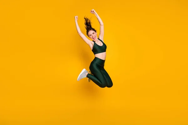 Pleine longueur photo de dame sportive sautant haut personne lever les poings porter costume de sport chaussures isolé fond de couleur jaune — Photo