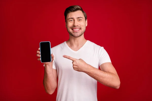 Retrato de belo homem positivo exibição direta dedo mostrando x-mas proposição isolada no fundo de cor vermelha — Fotografia de Stock