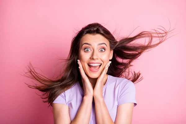 Portrait of impressed girl touch cheeks open mouth flowing hair dressed casual isolated on pink color background