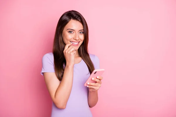 Retrato de menina sorridente menina segurar smartphone toque bochecha vestida violeta t-shirt isolada no fundo cor-de-rosa — Fotografia de Stock