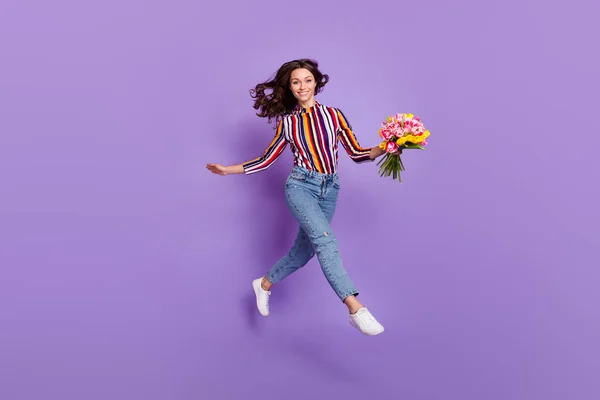 Πλήρες μήκος σώματος μέγεθος φωτογραφία της γυναίκας άλμα ψηλά χαμογελώντας κρατώντας λουλούδια τουλίπα απομονωμένο ζωντανό βιολετί φόντο χρώμα — Φωτογραφία Αρχείου