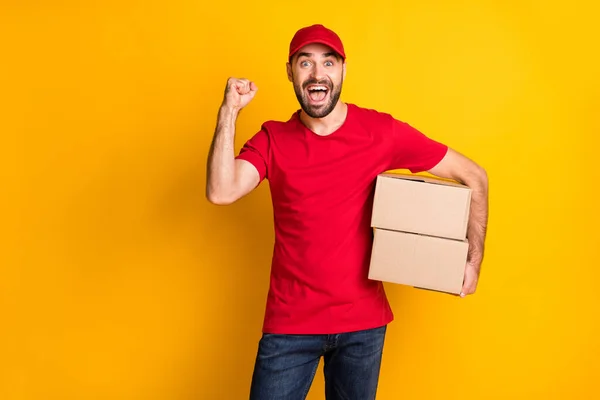 Portrait of attractive cheerful lucky guy mailman bringing parcels rejoicing isolated over bright yellow color background — Foto Stock