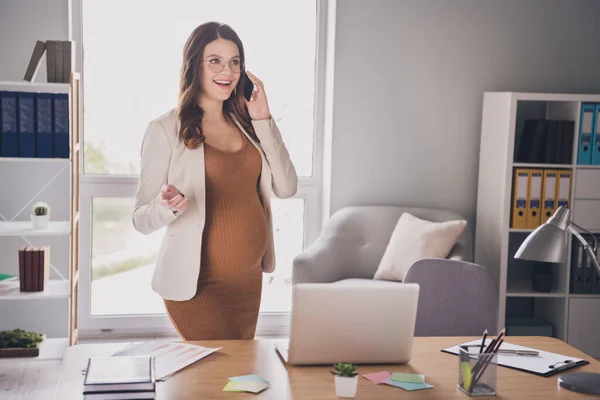 Fotografie těhotné ženy mluvící po telefonu stojící za stolem v moderní kanceláři — Stock fotografie