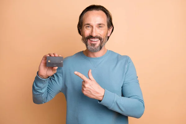 Foto retrato de homem apontando o dedo para o cartão de crédito isolado no fundo de cor bege pastel — Fotografia de Stock
