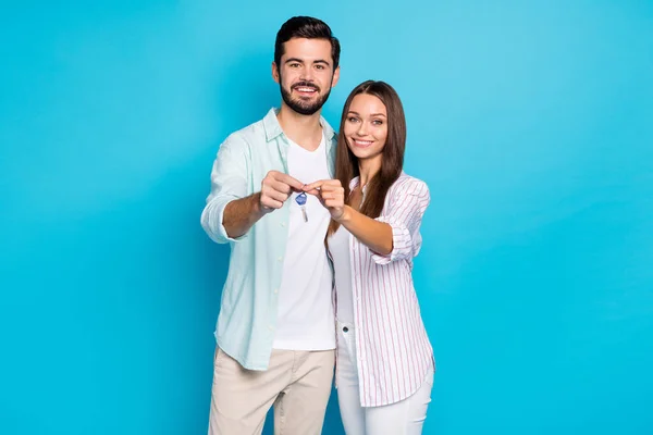 Photo of two persons hold hands together keys from new house toothy smile isolated on blue color background