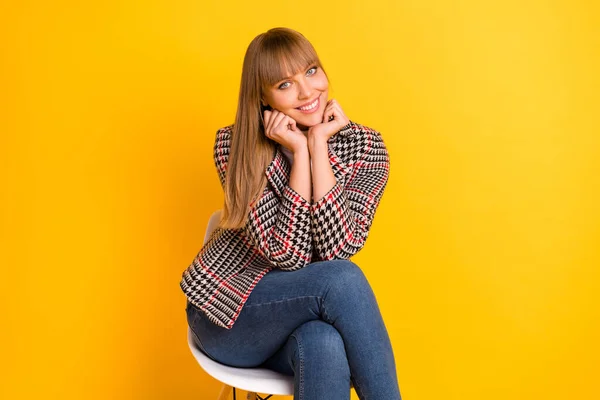 Photo of adorable satisfied person sit hands on cheeks look camera toothy smile isolated on yellow color background