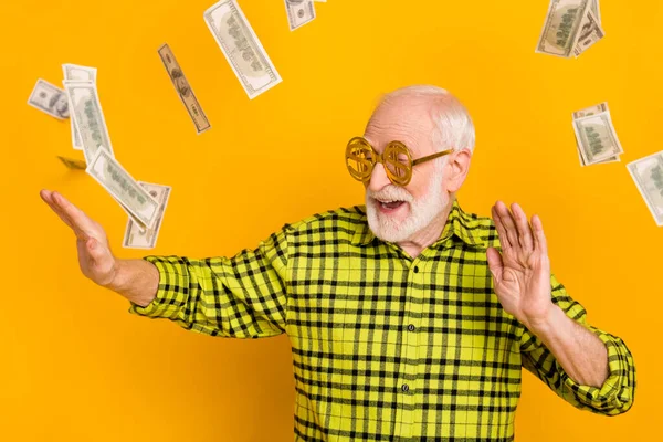 Photo of old man happy smile enjoy dance air fly cash dollars usd money wear spectacles isolated over yellow color background
