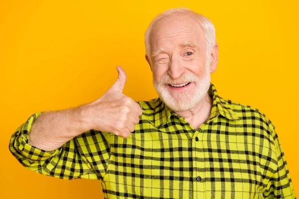 Foto de viejo hombre feliz sonrisa guiño ojo mostrar el pulgar hacia arriba fresco como anuncio consejo elección comentarios aislados sobre fondo de color amarillo —  Fotos de Stock