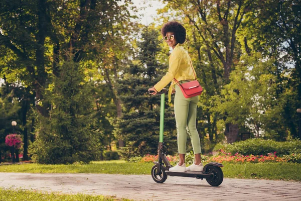 Foto retrato de la mujer conduciendo scooter verde al aire libre en el parque —  Fotos de Stock