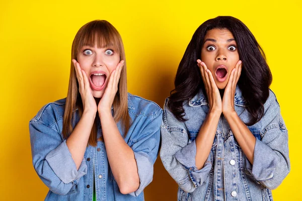 Photo of young shocked amazed surprised women hold hands cheek hear scary news isolated on yellow color background