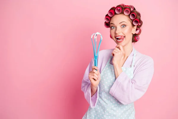 Photo of dreamy housewife dressed violet bathrobe red rollers holding blue whisk arm chin isolated pink color background — Stock Photo, Image