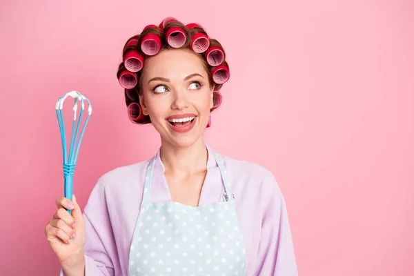 Foto van dromerige huisvrouw gekleed violet badjas rode rollen met blauwe garde op zoek lege ruimte geïsoleerde roze kleur achtergrond — Stockfoto