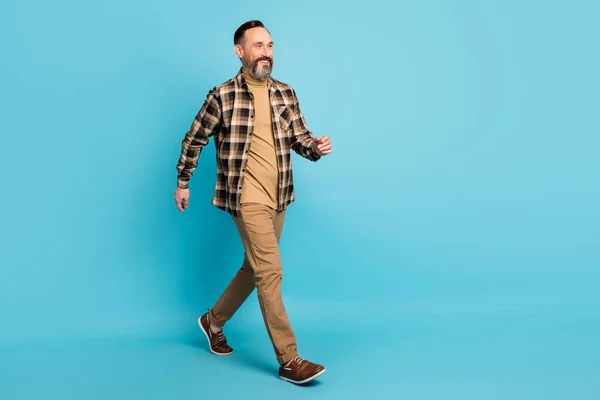 Full body photo of mature positive man walking into copy space isolated over blue color background — Stock Photo, Image