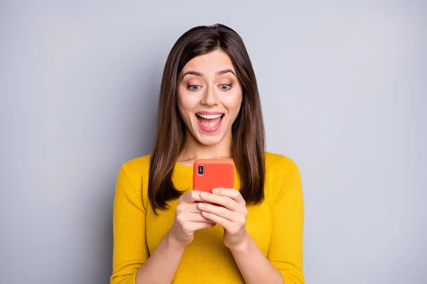Foto van jong blij enthousiast gek glimlachen vrolijk meisje met behulp van smartphone zie schokkend nieuws geïsoleerd op grijze achtergrond — Stockfoto