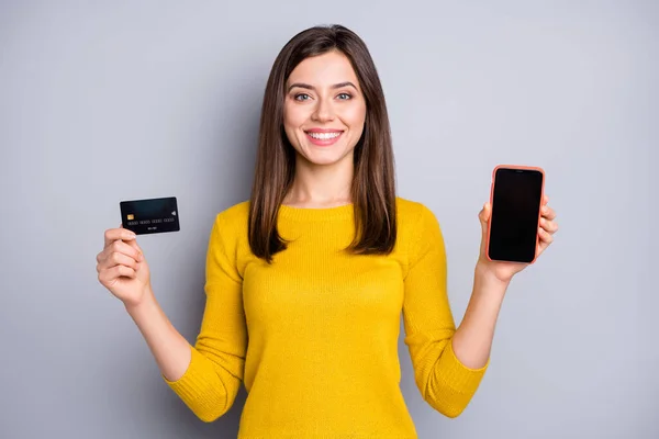 Портрет красивої контент весела дівчина тримає в руках сервіс гаджетів банківської картки ізольовано на сірому кольоровому фоні — стокове фото