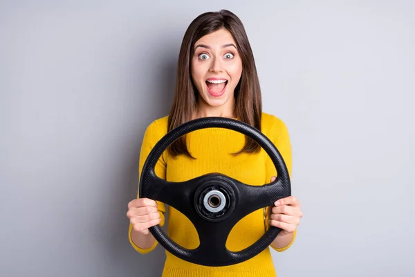 Retrato de chica alegre bastante sorprendido sosteniendo en las manos volante de conducción auto divertirse aislado sobre fondo de color gris —  Fotos de Stock