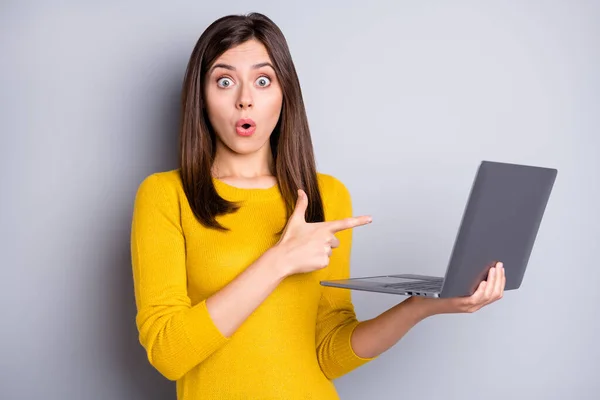 Foto van onder de indruk brunette mooie dame hold point laptop dragen gele trui geïsoleerd op grijze achtergrond — Stockfoto