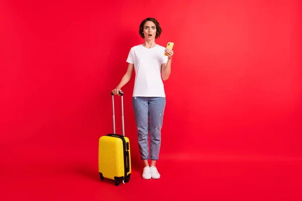 Longitud completa vista del tamaño del cuerpo de la atractiva chica loca preocupada utilizando gadget celebración bolsa noticias falsas aisladas sobre fondo de color rojo brillante —  Fotos de Stock